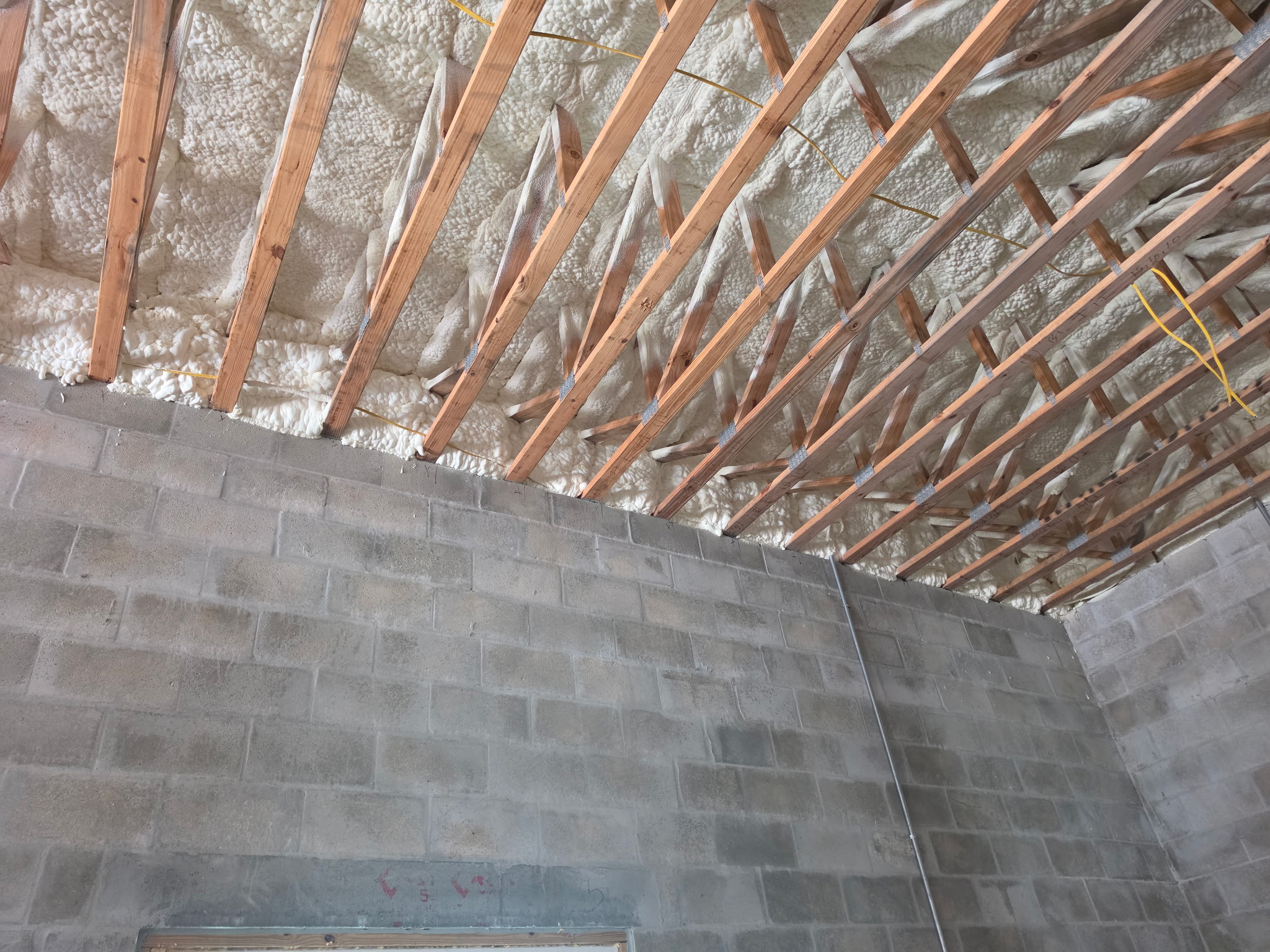 Spray foam insulation freshly applied to attic framing