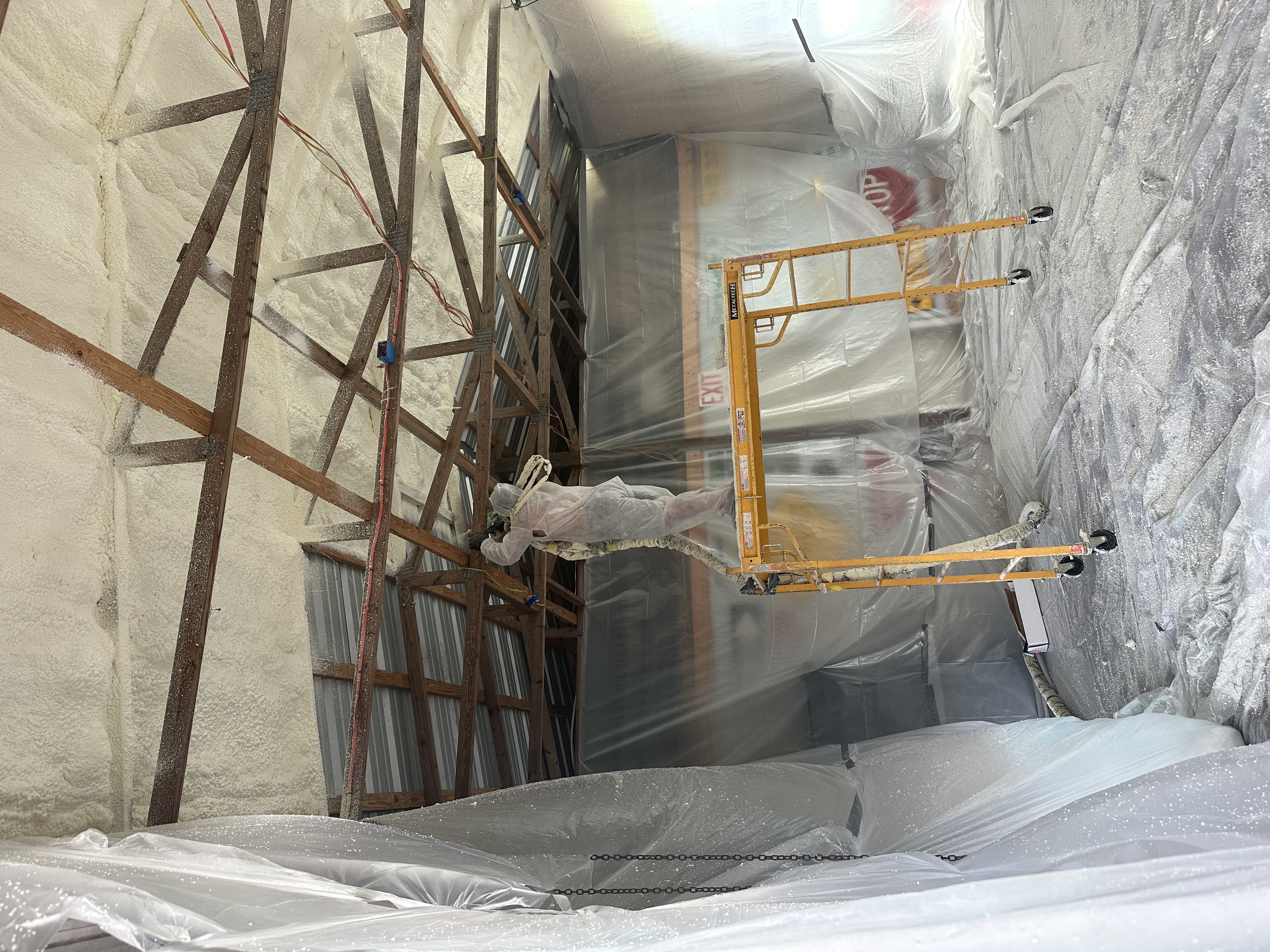 Insulflo crew applying spray foam from scaffolding on a building exterior